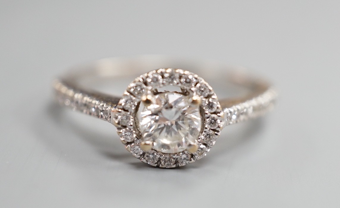 A modern 18ct white gold and single stone diamond ring with diamond chip circular setting and diamond chip set shoulders, from The Diamond Store, London